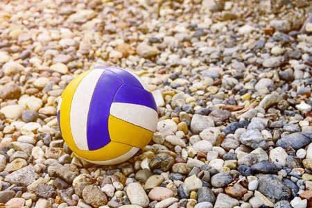 Close up of colored volleyball ball on a sea pebble beach. Summer beach games.の写真素材