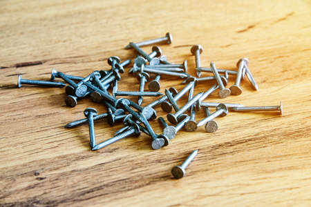 Heap of thin metal nails close up on wooden surface.の写真素材