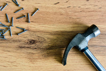Metal hammer with nails on a wooden table. Close up. Carpenter concept. Copy space.の写真素材