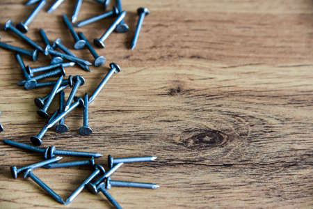 Heap of thin metal nails close up on wooden surface with copy space.の写真素材