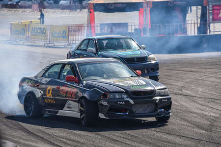 VLADIVOSTOK, RUSSIA - OCTOBER 02: Two Cars drift, Sports cars wheel drifts and a lot of smoke on the track. Russian drift show RDS without borders on October 02, 2021.のeditorial素材