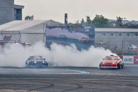 VLADIVOSTOK, RUSSIA - OCTOBER 02: Two Cars drift, Sports cars wheel drifts and a lot of smoke on the track. Russian drift show RDS without borders on October 02, 2021.のeditorial素材
