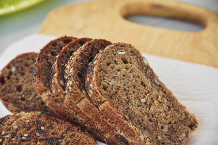 Sliced rye bread with sunflower and poppy seeds on rustic wooden background. Healthy food still...