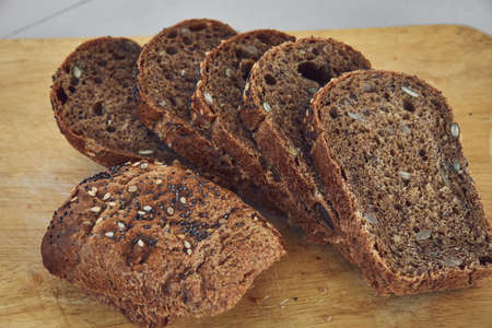 Sliced rye bread with sunflower and poppy seeds on rustic wooden background. Healthy food still...