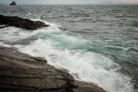 sea waves with splashes and foam wash over the rocky stones.の写真素材