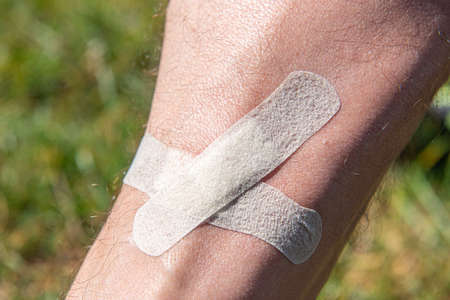 male shin wound sealed by adhesive plaster close up.の写真素材