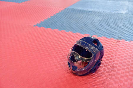 Taekwondo head guard for children on a training mat with copy space.