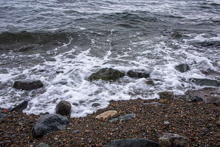large stones and small pebbles on the shore are washed by the sea.の写真素材