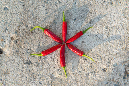 Many small hot red chili peppers close-up, lying on a stone background. Rustic background. Top view,...