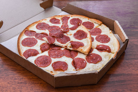 Pepperoni Pizza in open carton box on wooden table, closeup.の写真素材