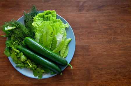 fresh cucumbers, lettuce, dill, cilantro and green peas on a plate. Spring salad, spring greens, healthy food from natural products. Vegetarian food. copyspace.の写真素材