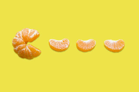 Mandarin and mandarin slice on a yellow background. pacman game. Tangerine Pacman. Vitamin C.の写真素材