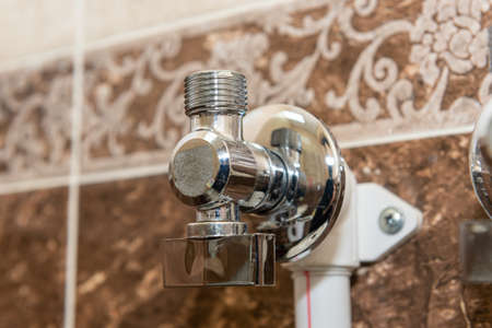 Water taps for connecting a boiler on tiled wall. The faucet with connected pipes is mounted on the wall. close up.の写真素材