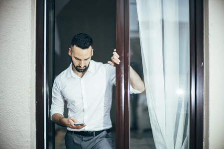 Attractive man with beard working posing at home window.の写真素材