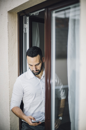 Attractive man with beard working posing at home window.の写真素材