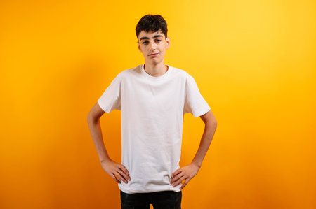 Smiling teen boy in white t-shirt, yellow background.の写真素材