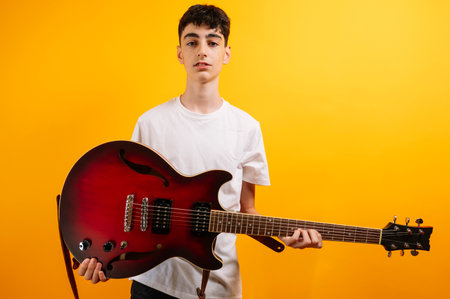 Teenage boy proudly displays his electric guitar.の写真素材