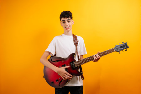 Teenage boy proudly displays his electric guitar.の写真素材