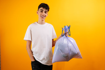 Teenager holding a purple trash bag, smiling.の写真素材