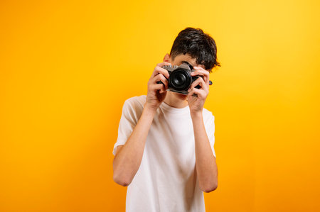 Teenager with camera, yellow background.の写真素材