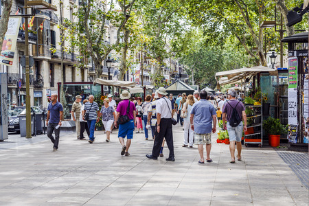 BARCELONA, SPAIN - JUNE 29,2014: Tourists walk famous Rambla street in Barcelona, Spain. According...
