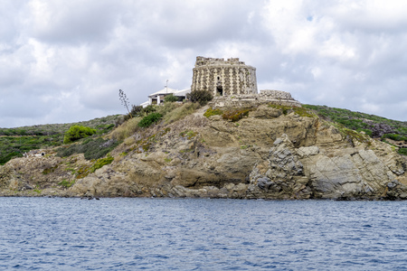 Defensive tower Sa Mesquida English coastal is located on a high rock in the center of the bay, in Menorca, Spainの写真素材