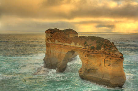 Ocean water splashing on London Bridge, a natural rock formation, along Great Ocean Road in Australia.の写真素材