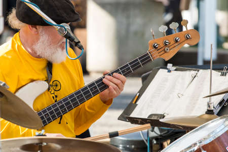 Portland musician Ray Mann of band Boomeration performing live music on stage at a farmer's market in Portland Oregon playing guitar drums and singing simultaneouslyのeditorial素材