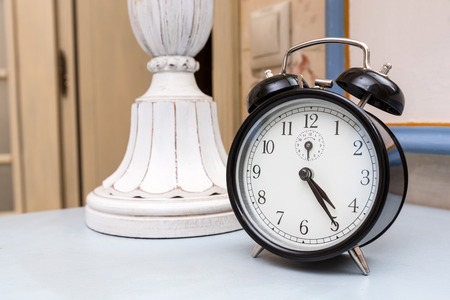 Black vintage alarm clock on a blue table in a hotel roomの写真素材