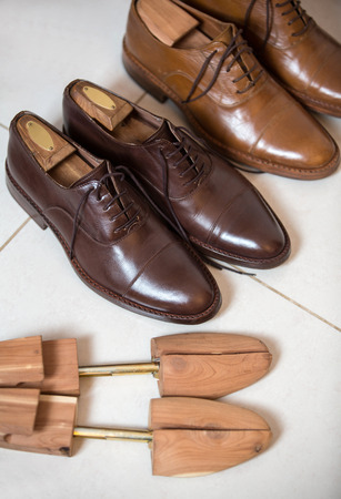 Two pairs of brown handmade classic men's shoes  with a shoe pads and stretchers inside and beside the shoesの写真素材