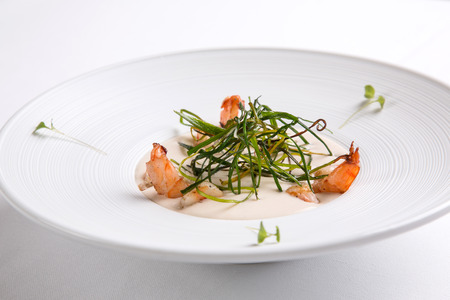 Cream soup with shrimps in a white round plate on a white backgroundの写真素材