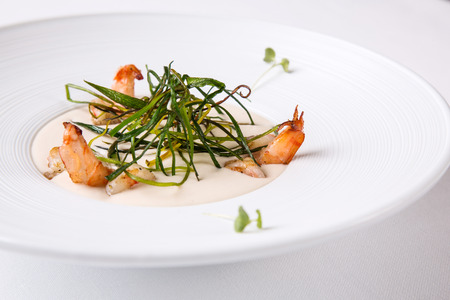 Cream soup with shrimps in a white round plate on a white backgroundの写真素材