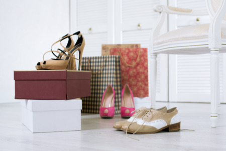 Three pairs of just purchased and unboxed shoes on a floor of a wardrobeの写真素材