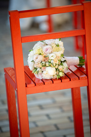 Wedding bouquet lying on a red chair on a locationの写真素材
