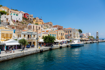SYMI, GREECE - JUNE 12, 2015: The main street along the coast in Yialos harbour on June 12, 2015 on Symi island, Greece. Symi is easy and most popular destination for day tripping from Rhodes island.のeditorial素材