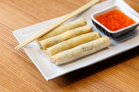 Fried spring rolls with chicken and vegetables on a rectangle plate in asian restaurant with ginger...