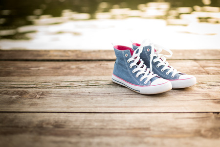 pair of jeans sneakers standinf on a wooden pier over the water backgroundの写真素材