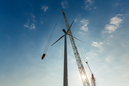 Industrial crane installing wind tubine. Renewable wind energy concept の写真素材