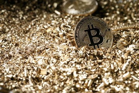 Golden metal coin as symbolic version of Bitcoin on a background of metal shavings . Cryptocurrency and new digital payment system concept. の写真素材