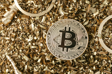 Golden metal coin as symbolic version of Bitcoin on a background of metal shavings . Cryptocurrency and new digital payment system concept. の写真素材