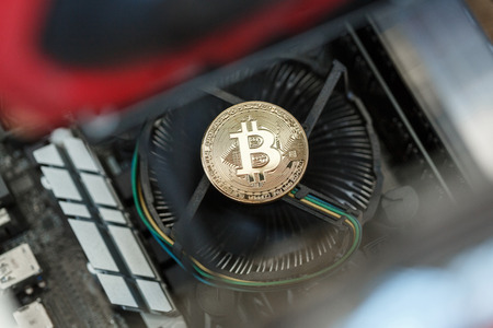 Golden metal coin as symbolic version of Bitcoin on a background of computer mining electronic parts . Cryptocurrency mining process concept. の写真素材