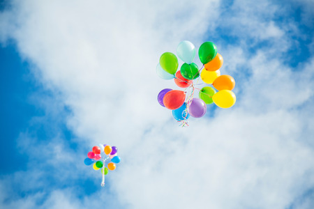 Group of multicolored helium filled balloons in the skyの写真素材
