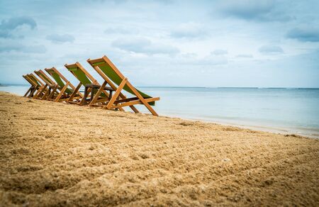 Five empty green beach chairs facing the ocean. Vacation beach relax conceptの写真素材