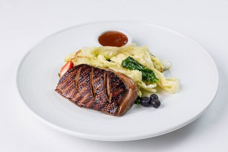 Grilled duck breast with vegatables and berry suase on a white plate. Restaurant servingの写真素材