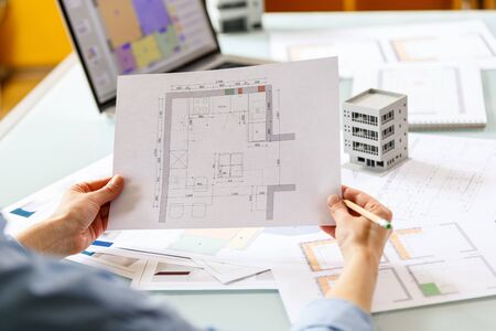 Interior designer working with an apartment plans in a studio, with blueprints and laptop on a table. Architectural desigh bureau working conceptの写真素材