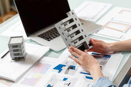 Close up of a house model in architect's  hands in a construction bureau. Architectural and...