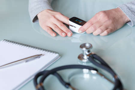 Female patient hand measuring oxygen saturation and pulse using portable oximeter. Health care conceptの写真素材