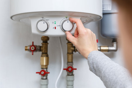 Female hand puts of electric water heater (boiler) in economy mode. Household enegry saving equipmentの写真素材