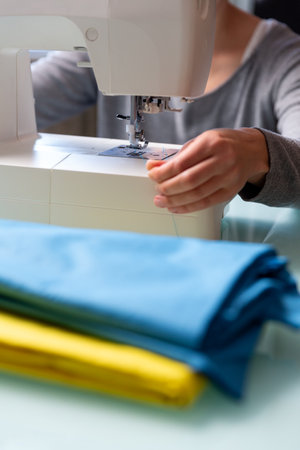 Close up shot of Tailor's female hands preparing sewing machine.の写真素材