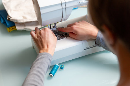 Close up shot of Tailor's female hands preparing sewing machine.の写真素材